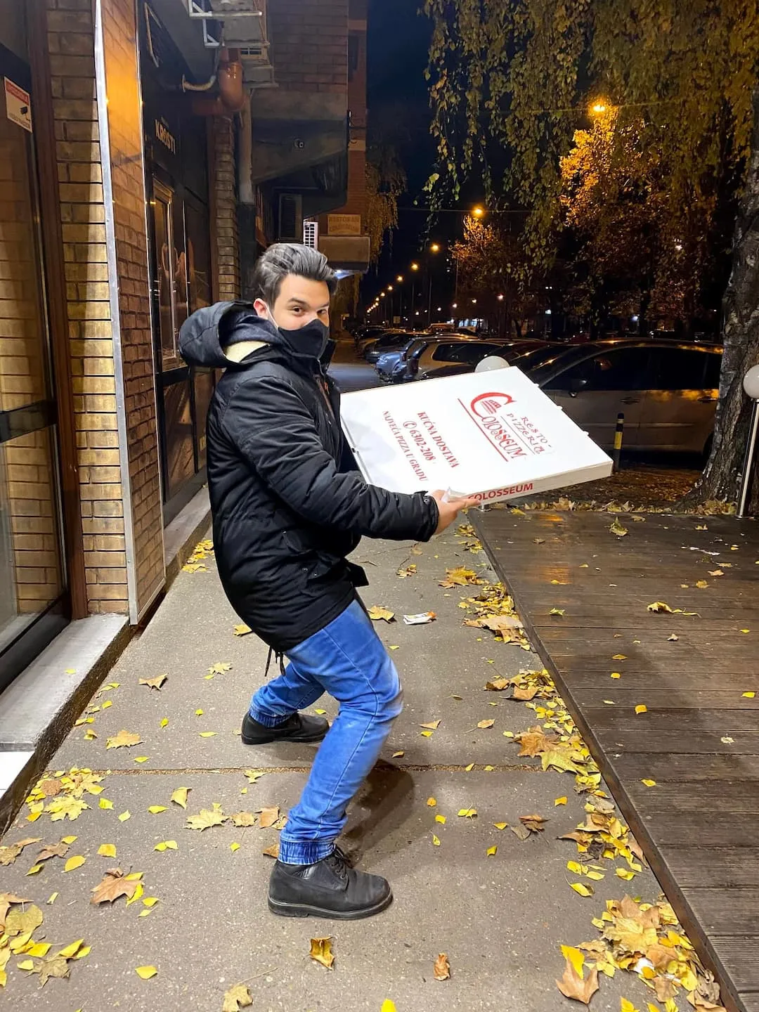 Holding a meter long pizza in a box on a street.